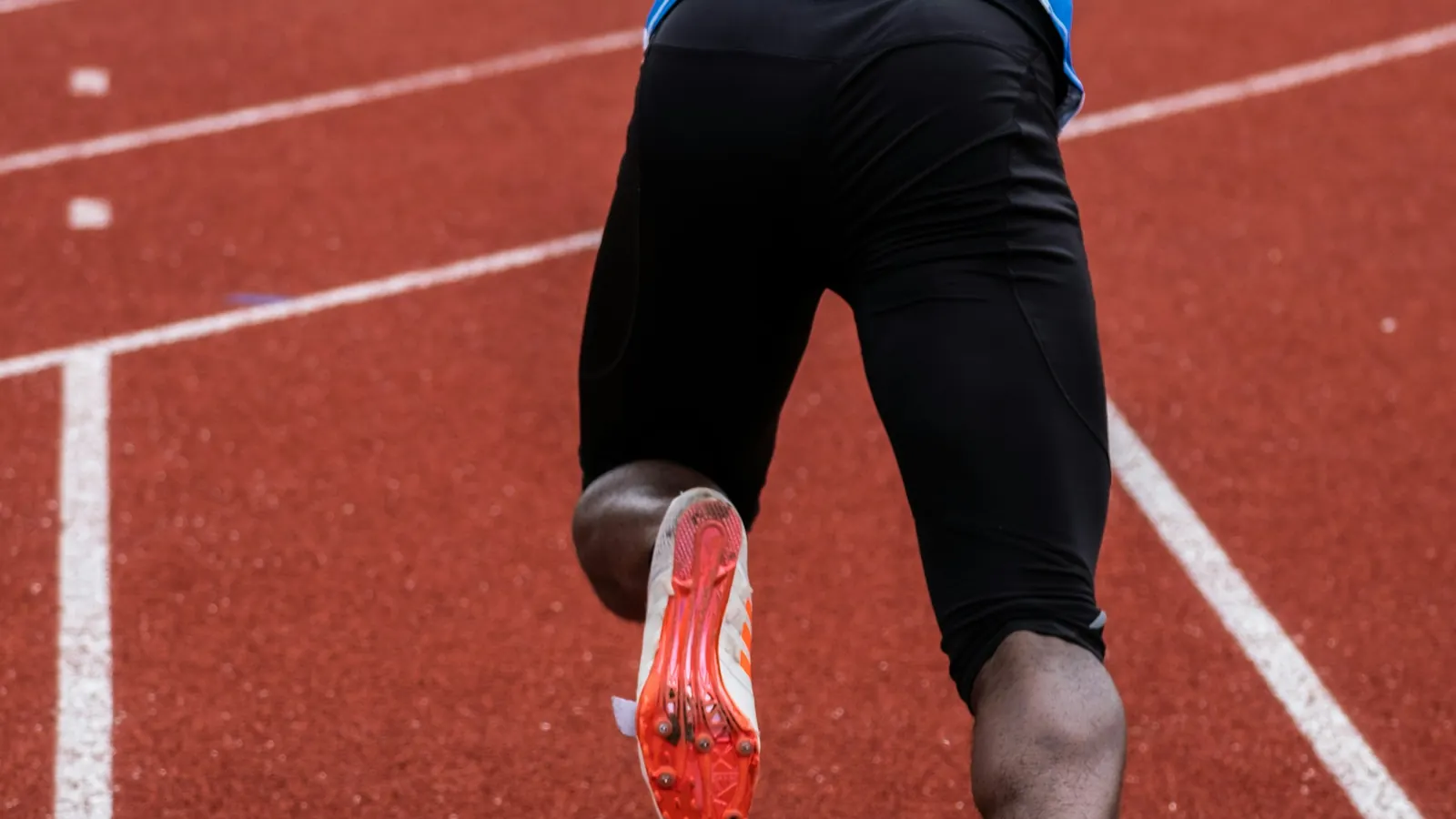 A sprinter mid-stride on a red running track